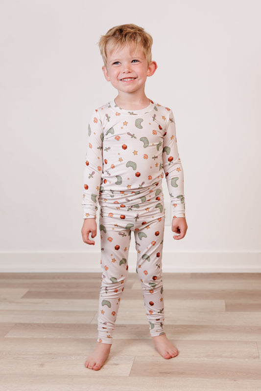 Child wearing a long-sleeve pajama set with a pattern on a plain background