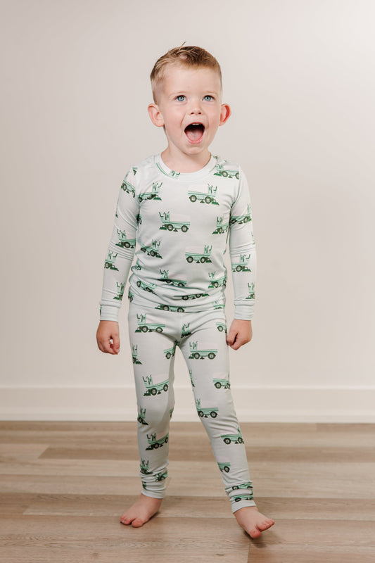 Child wearing a green and white pajama set with zamboni pattern on a wooden floor.