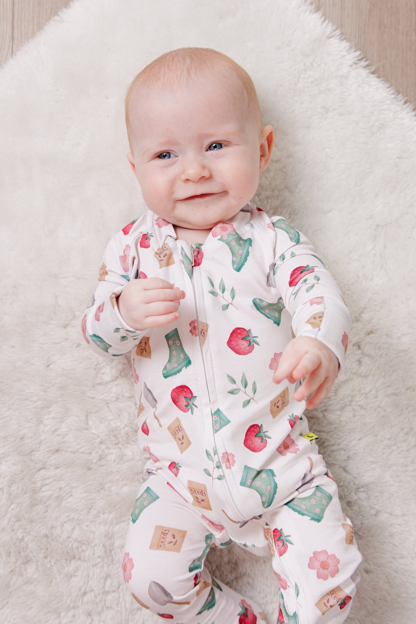 Baby in a floral gardening onesie lying on a fluffy white blanket