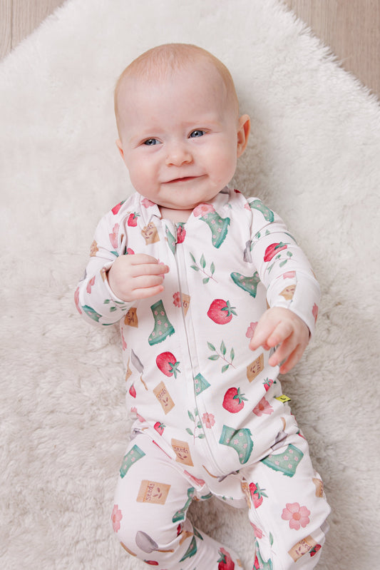 Baby in a floral gardening onesie lying on a fluffy white blanket